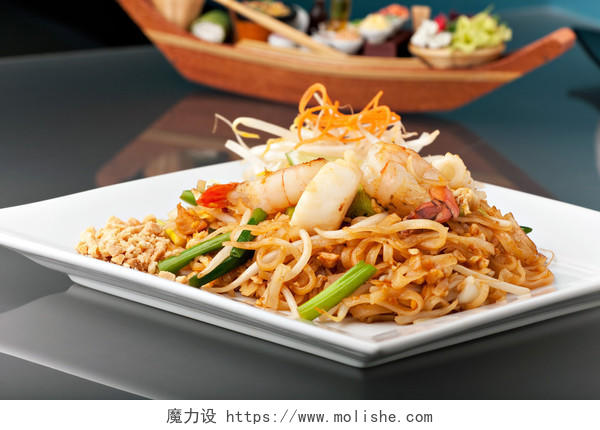海鲜垫泰国菜的搅拌炒米粉白色方形盘子上的用筷子和接枝胡萝卜做装饰